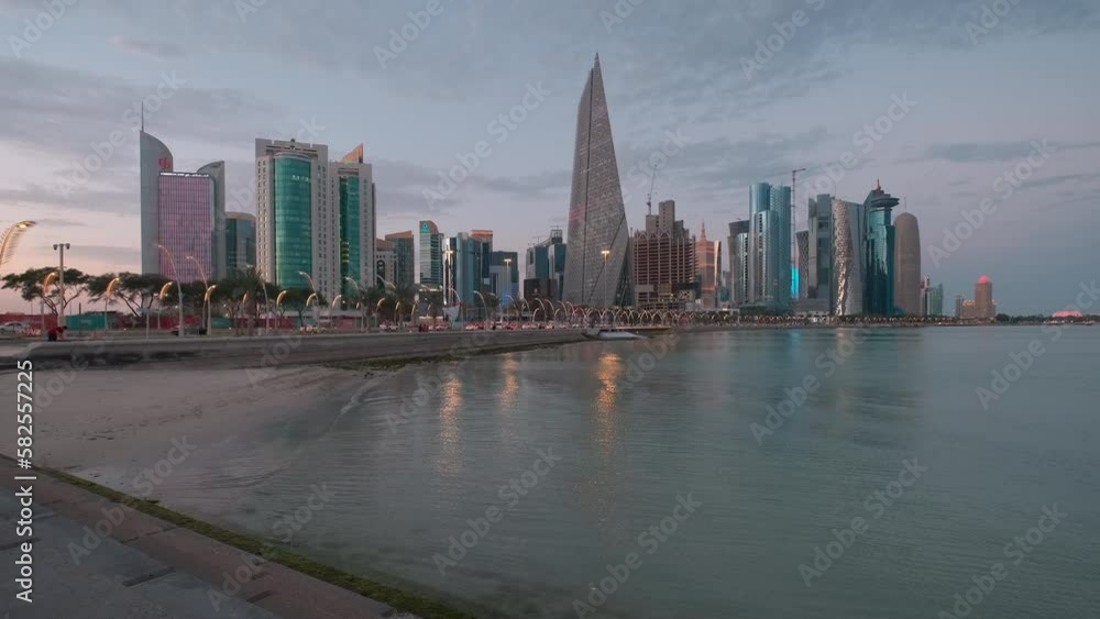 Doha Qatar skyline from corniche promenade at sunset showing West Bay skyscrapers lights reflected in the Arabic gulf Doha Qatar skyline from corniche promenade at sunset showing West Bay skyscrapers lights reflected in the Arabic gulf
