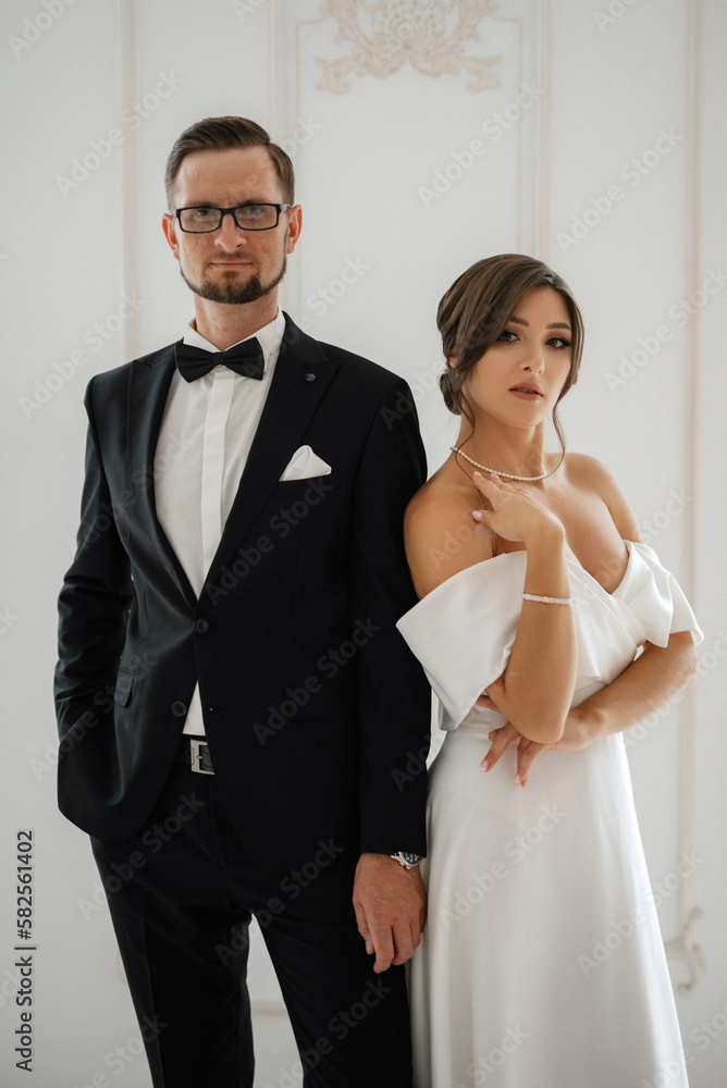 groom in a black suit tie and the bride in a bright studio groom in a black suit tie and the bride in a bright studio