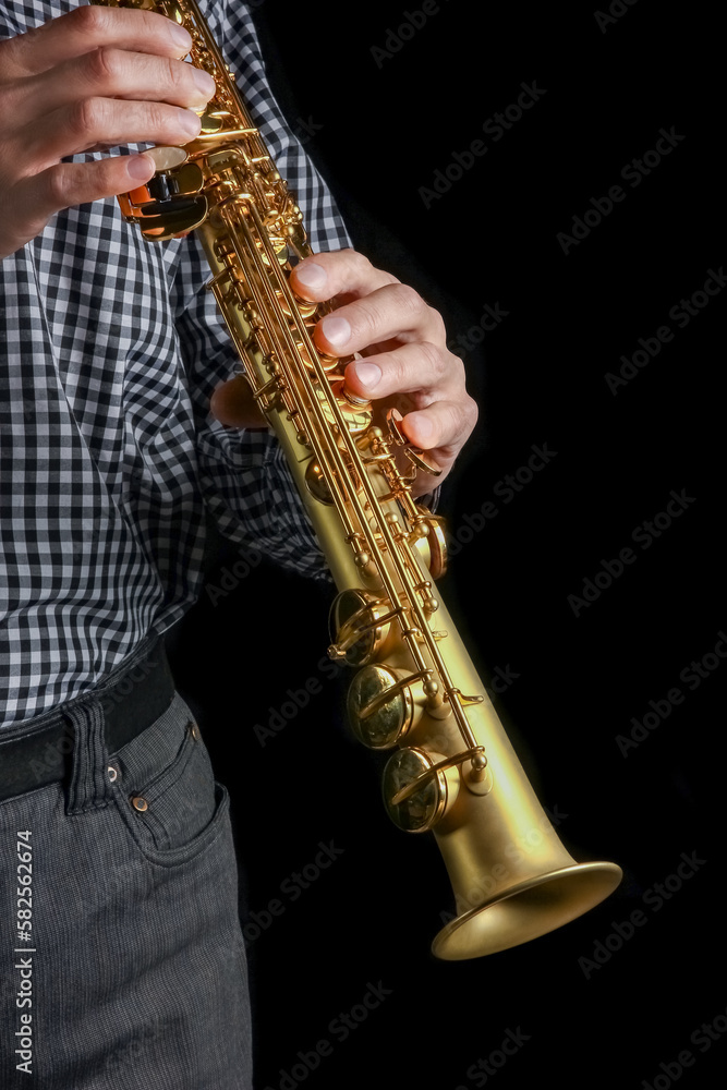 Naklejka premium soprano saxophone in hands on a black background