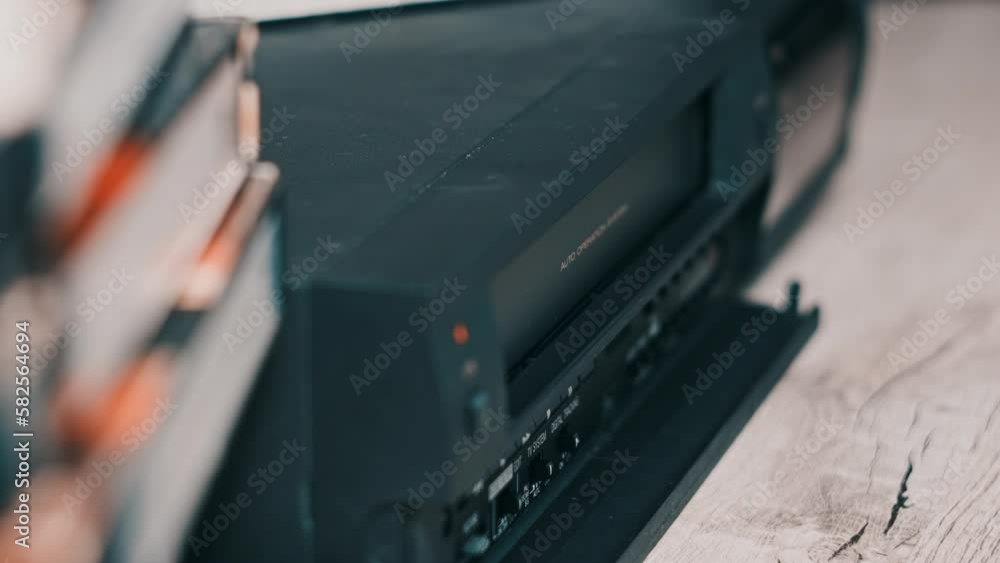 Eject VHS tape cassette from VCR player. Male hand pushes a button and