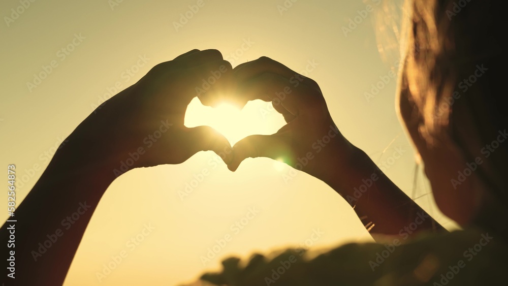 Fototapeta premium Girl happiness summer dream shaped hand heart sunlight forming happy finger. fingers freedom fingers park holiday summer shining silhouette made. figure shape shining freedom made hand hand happy