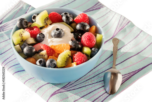 Freshly prepared delicious healthy fruit salad for breakfast in a blue ceramic bowl. White isolated background.
