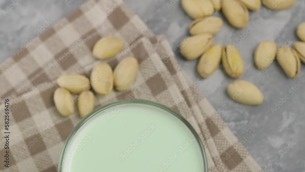 Pistachio milk in a glass on a gray background. Lactose free pistachio milk and pistachios on a linen napkin. Top view camera Pistachio milk in a glass on a gray background. Lactose free pistachio milk and pistachios on a linen napkin. Top view camera