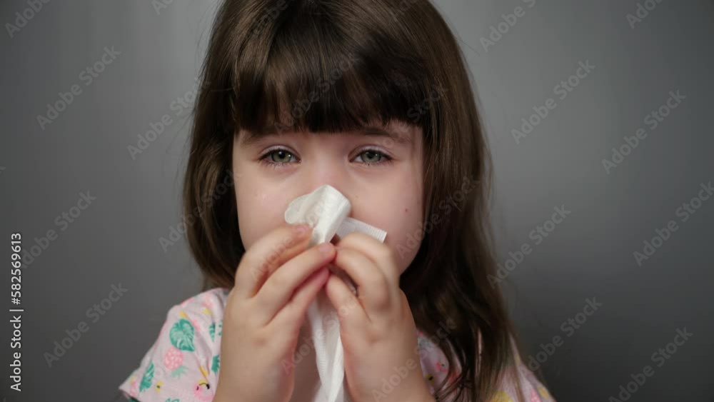 Little cute girl blows her nose in a napkin, seasonal allergies, rhinitis in a child. Closeup isolated portrait of a little girl, sick with a cold, ODS. Little cute girl blows her nose in a napkin, seasonal allergies, rhinitis in a child. Closeup isolated portrait of a little girl, sick with a cold, ODS.
