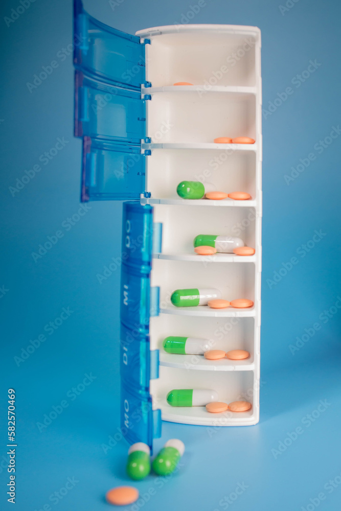Plastic container with various pills on a blue background. Planning the use of tablets Plastic container with various pills on a blue background. Planning the use of tablets
