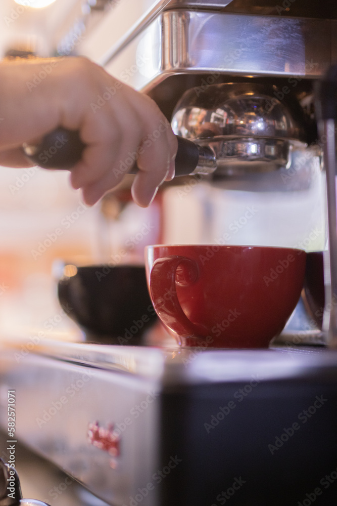 Fototapeta premium Bartender working on coffee machine in red cup and black cup
