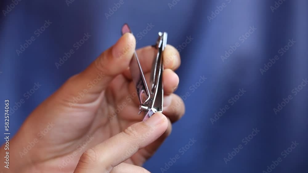 a woman is cutting her fingernails using nail clippers. Cutting nails is a form of body care. a woman is cutting her fingernails using nail clippers. Cutting nails is a form of body care.