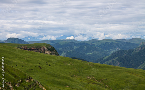 Panoramic view of green mountains and hills and a haze from the Bermamyt plateau in Karachay-Cherkessia in Russia on a cloudy summer day and a space for copy