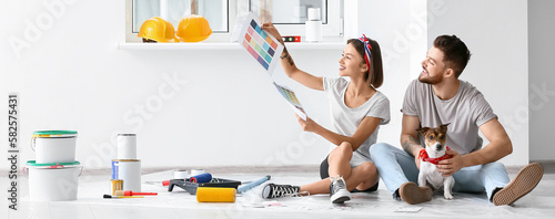 Quadro su tela Happy young couple with cute dog choosing color of paint for repair in their new