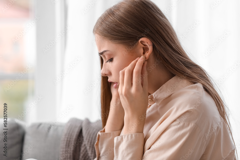 Young woman with ear plugs suffering from loud noise at home, closeup Young woman with ear plugs suffering from loud noise at home, closeup