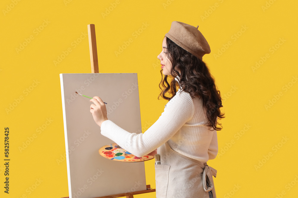 Teenage artist with brush and paint palette drawing on yellow background - obrazy, fototapety, plakaty 
