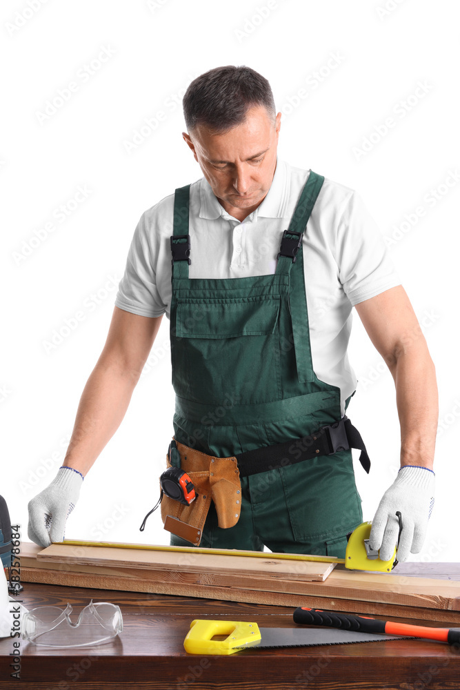 Mature carpenter measuring wooden plank at table on white background Mature carpenter measuring wooden plank at table on white background
