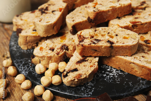 Board with delicious biscotti cookies and hazelnuts on wooden background photo
