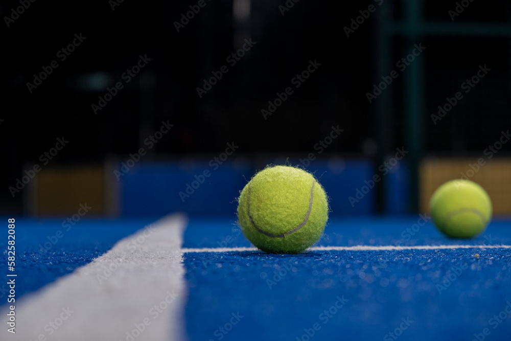Selective focus, two balls and the line of a blue paddle tennis court