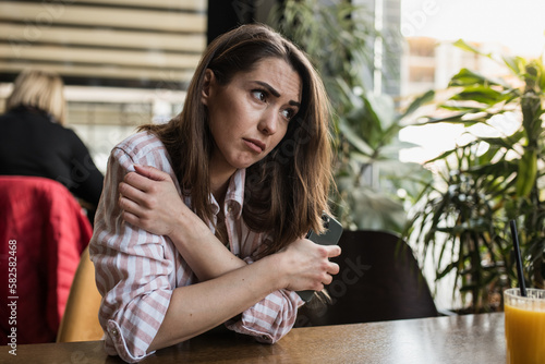 Young depressed woman sitting in a restaurant crippled with anxiety 