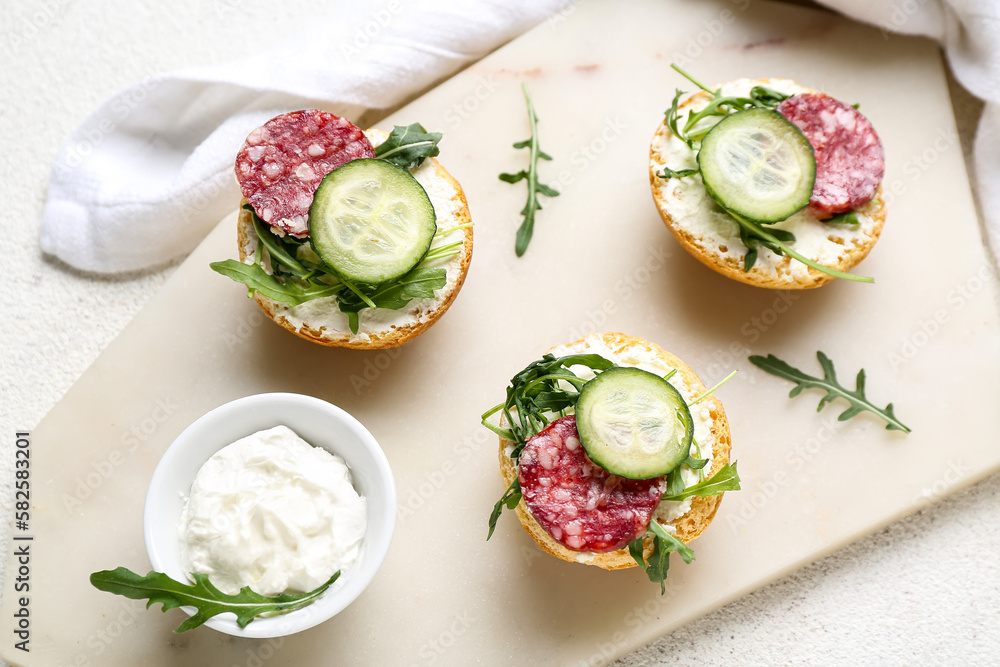 Board with delicious sandwiches and cream cheese on light background, closeup Board with delicious sandwiches and cream cheese on light background, closeup