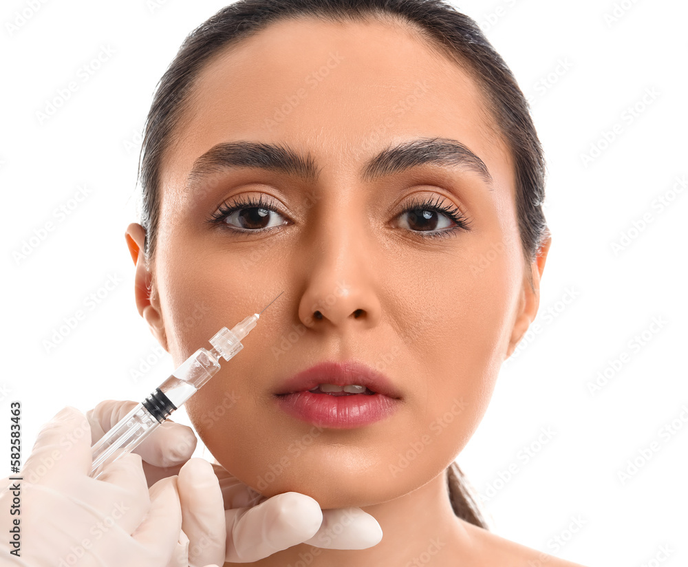 Young woman receiving filler injection in face against white background