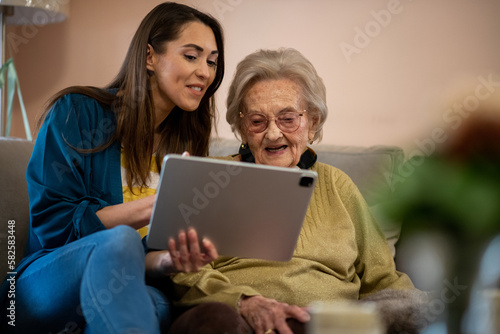 Senior woman and nurse using digital tablet to communicate with family members.