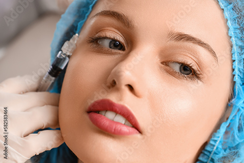 Young woman receiving filler injection in beauty salon