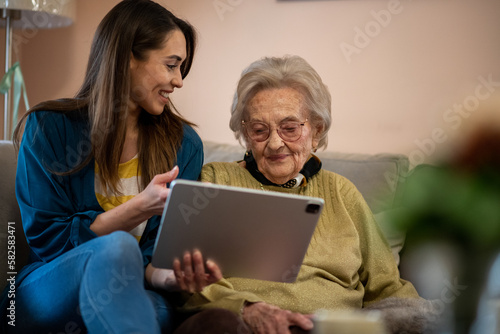 Nurse and senior woman reviewing medical records on a digital tablet.