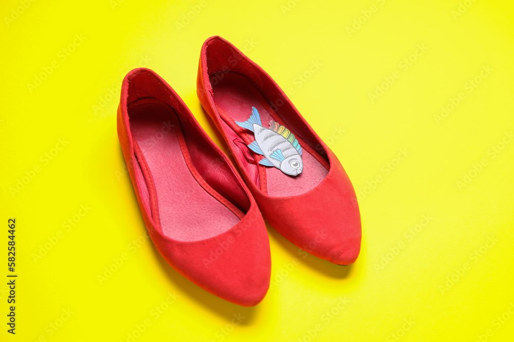 Female shoes with paper fish on yellow background. April Fools' Day celebration Female shoes with paper fish on yellow background. April Fools' Day celebration