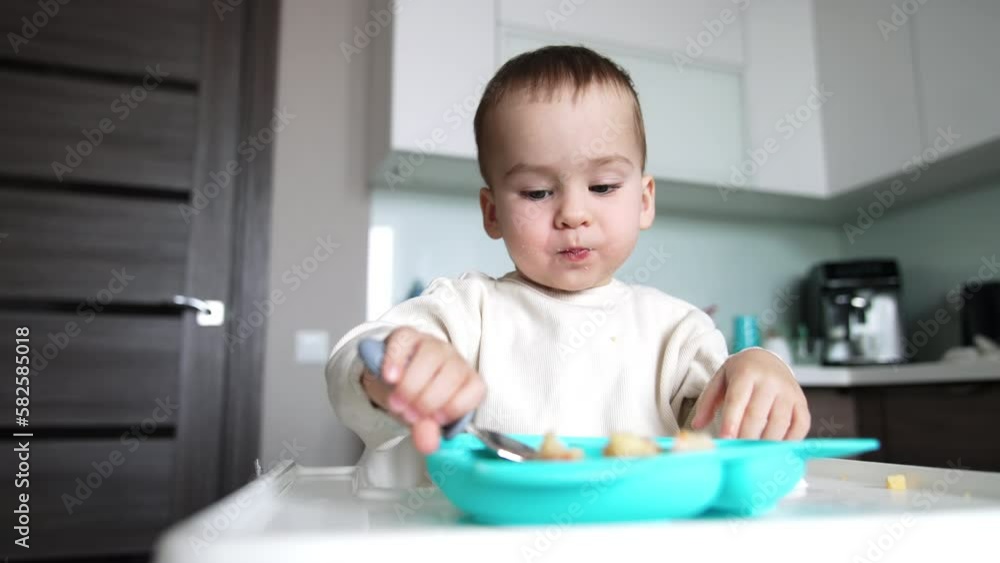 Little kid eating from plate using spoon. Baby is growing , developing and learning. Little kid eating from plate using spoon. Baby is growing , developing and learning.