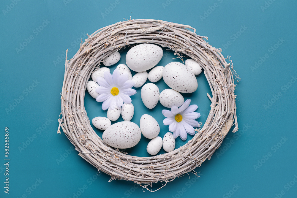 Wreath with Easter eggs and beautiful daisy flowers on blue background