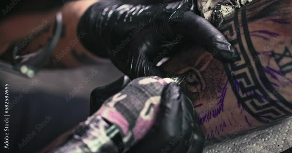 Close up tattoo artist shows the process of getting black tattoos with paint. The master works in black sterile gloves. Master tattoo artist in studio. Close up tattoo artist shows the process of getting black tattoos with paint. The master works in black sterile gloves. Master tattoo artist in studio.