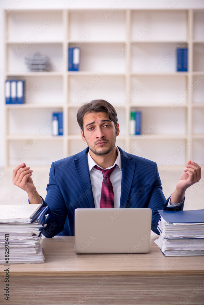 Young male employee and too much work in the office Young male employee and too much work in the office