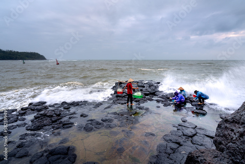 "Thach Ky Dieu Tau" in Son Tinh, Quang Ngai, Vietnam - Fishermen work on a rock against big waves at "Thach Ky Dieu Tau" in Son Tinh, Quang Ngai, Vietnam