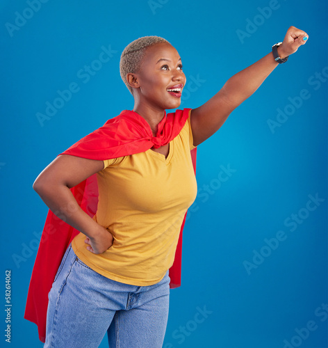 Fotografie Black woman, superhero cape and flying in studio, blue background and pop culture fashion