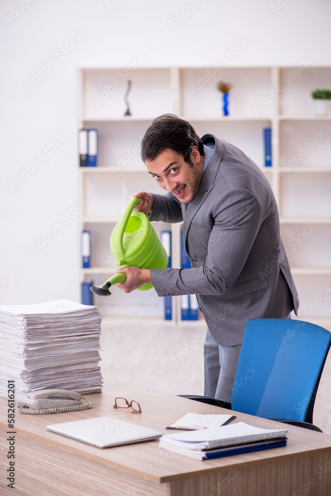 Young male employee watering papers by can