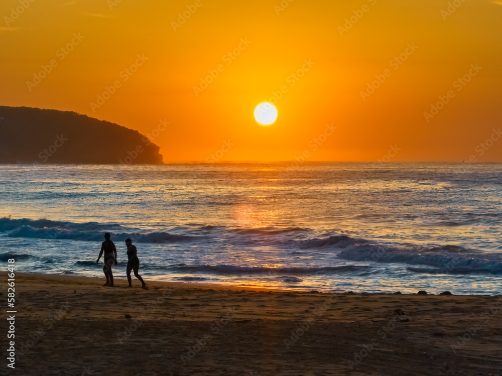 Soft hazy sunrise seascape, orange sky, people silhouettes and full sun Soft hazy sunrise seascape, orange sky, people silhouettes and full sun