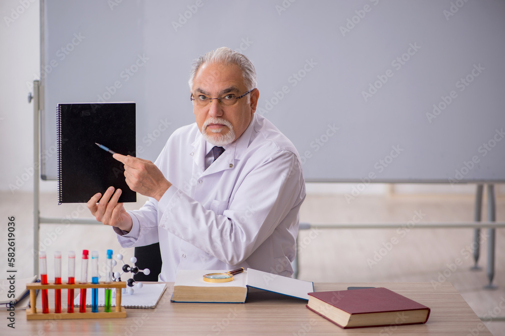 Old male chemistry teacher in the classroom Old male chemistry teacher in the classroom