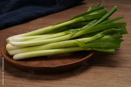 A pile of green onions on a wooden plate