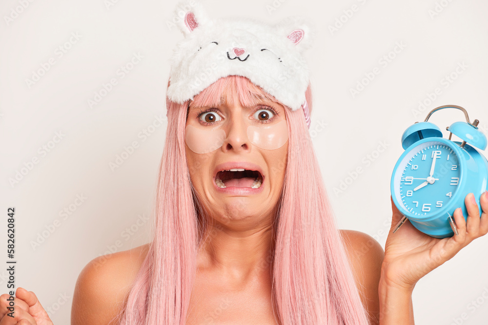 Lovely girl with pink hair slept through the alarm clock posing on pink