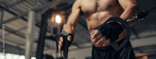 Fotografi Selective focus hand, Sport man workout weight training pump up arm and shoulders muscles on exercise machine in fitness gym
