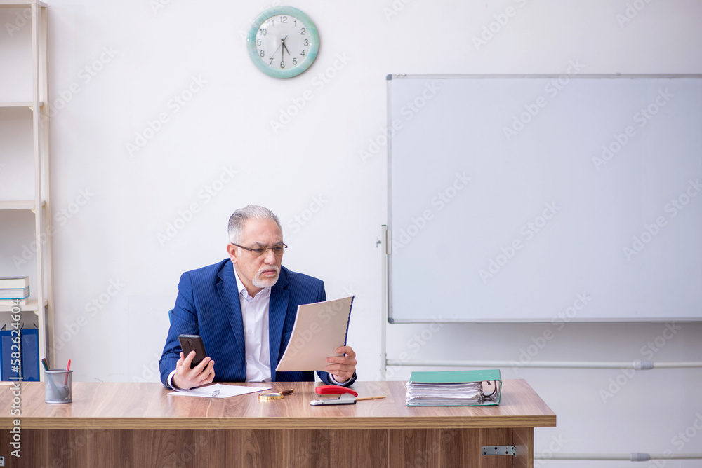 Old male teacher in the classroom Old male teacher in the classroom