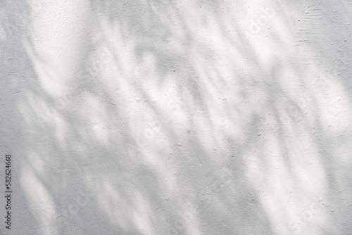 White cement or stone wall background and rough textured with shadow of Tree leaves and sunlight