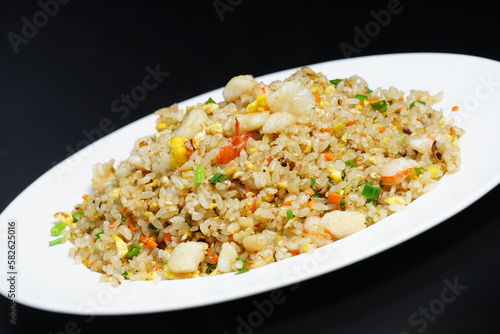 A plate of seafood scary Yangzhou fried rice on black background