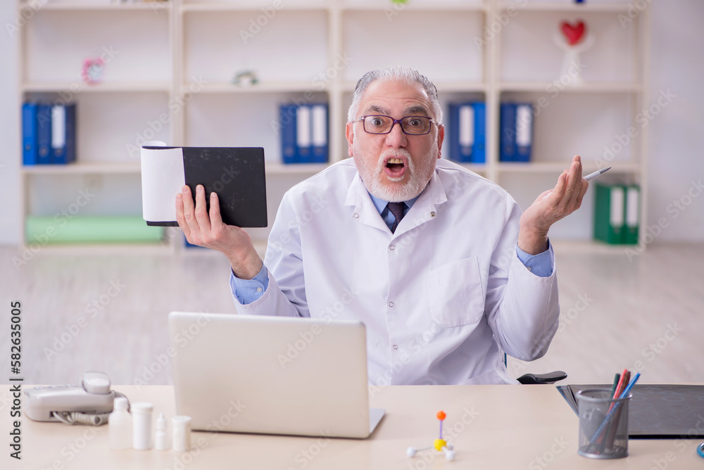 Old male doctor working in the clinic Old male doctor working in the clinic