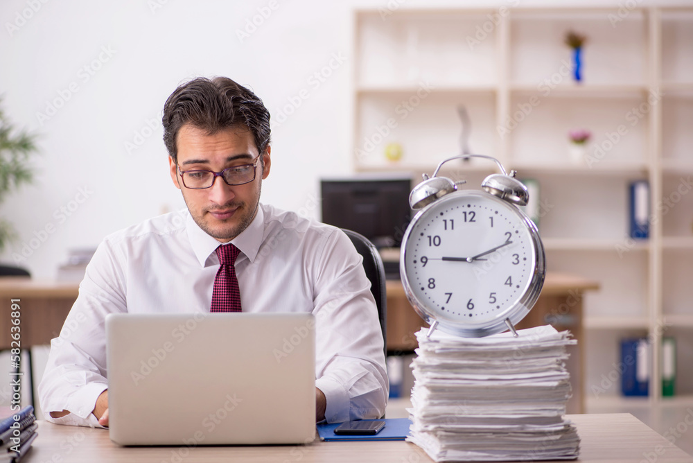 Young male employee in time management concept Young male employee in time management concept