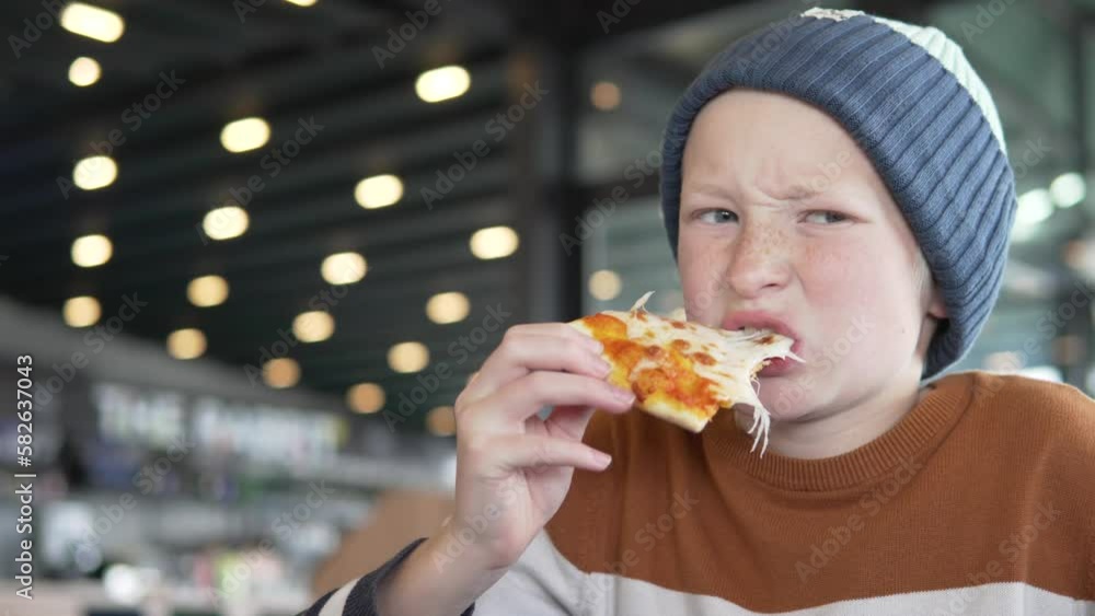 A hungry schoolboy boy eats a pizza margarita in a fast food restaurant A hungry schoolboy boy eats a pizza margarita in a fast food restaurant