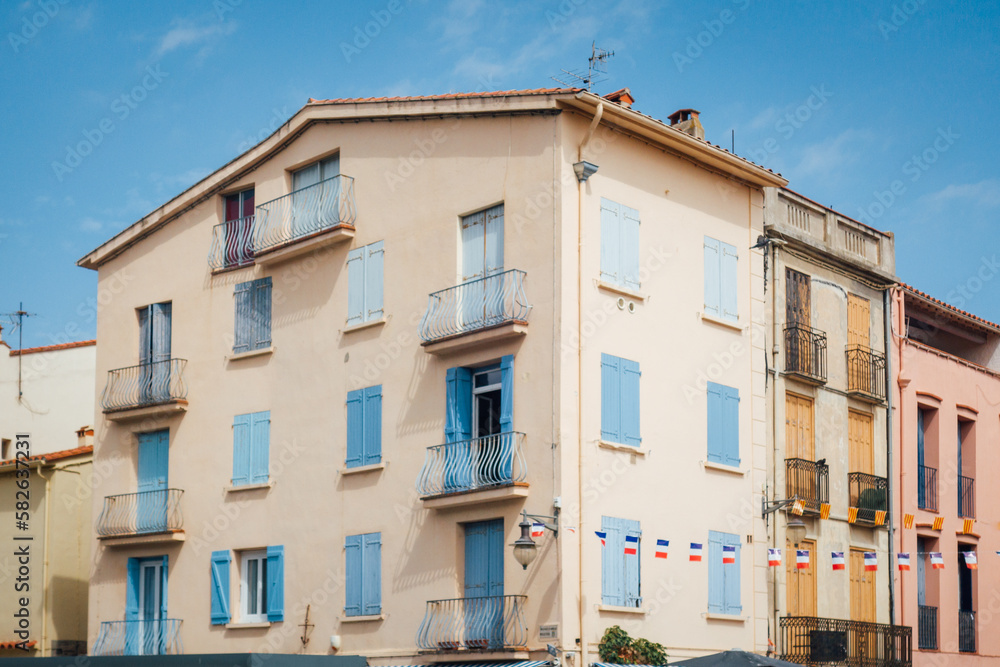 Obraz premium Une façade d'immeuble à Collioure. Un bâtiment à Collioure. Immeuble du sud de la France. Maison méditerranée. Une façade rose avec des fenêtres bleues.