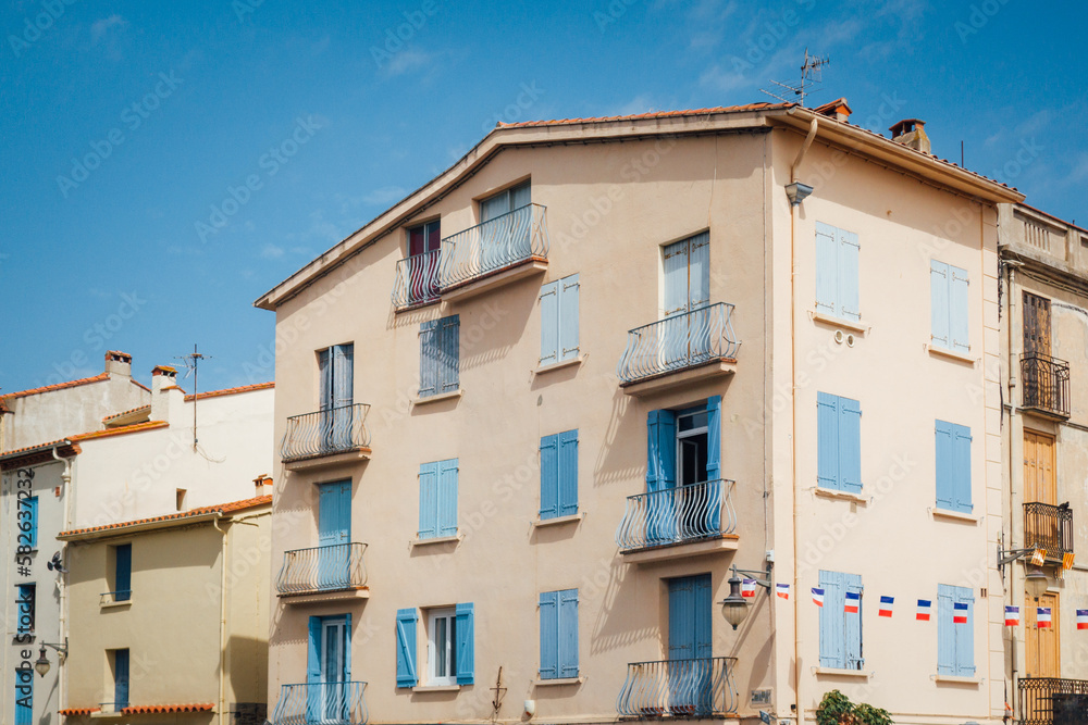 Une façade d'immeuble à Collioure. Un bâtiment à Collioure. Immeuble du sud de la France. Maison méditerranée. Une façade rose avec des fenêtres bleues.