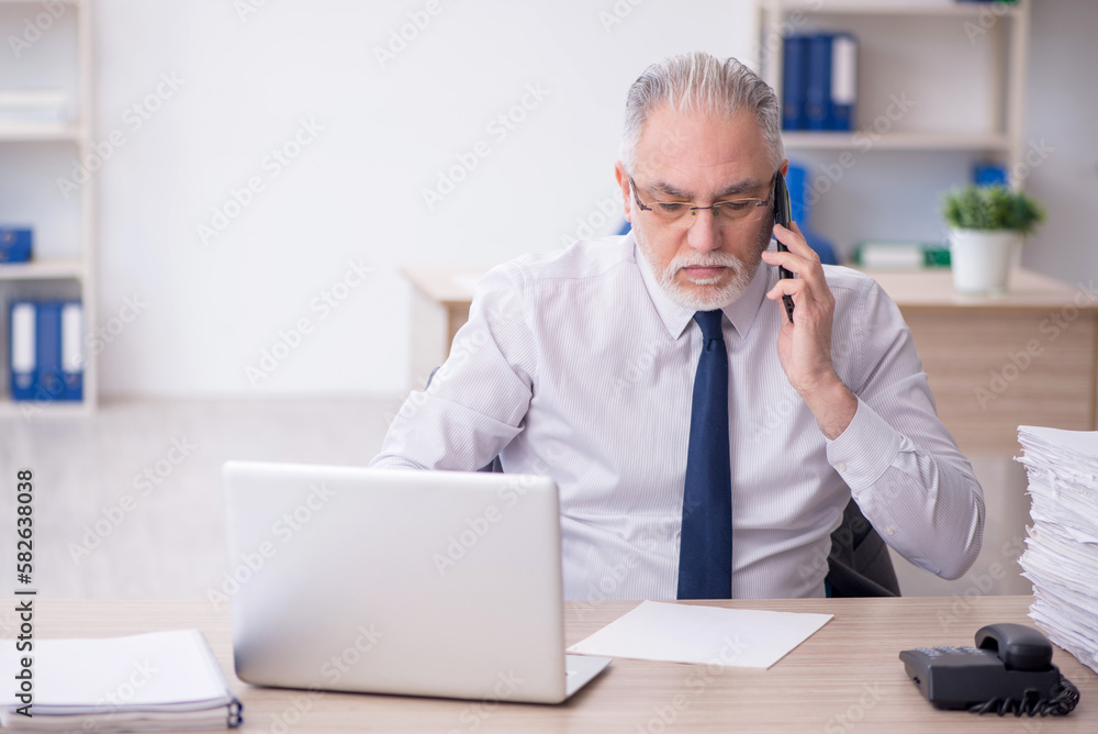 Old male employee working in the office Old male employee working in the office