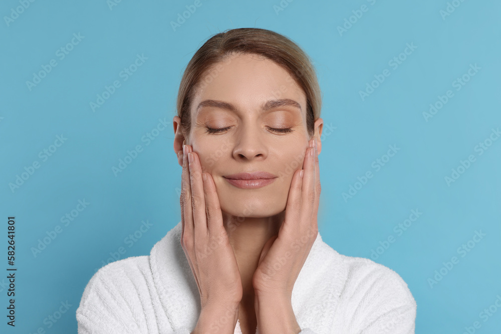 Woman massaging her face on turquoise background Woman massaging her face on turquoise background