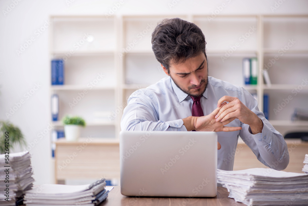 Young male employee and too much work in the office Young male employee and too much work in the office