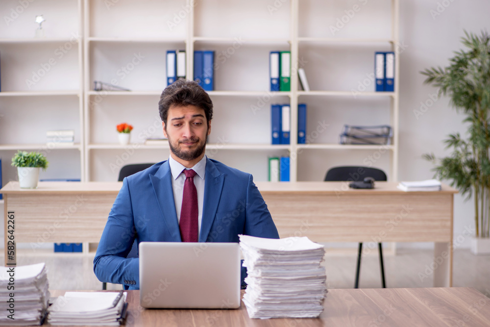 Young male employee and too much work in the office Young male employee and too much work in the office
