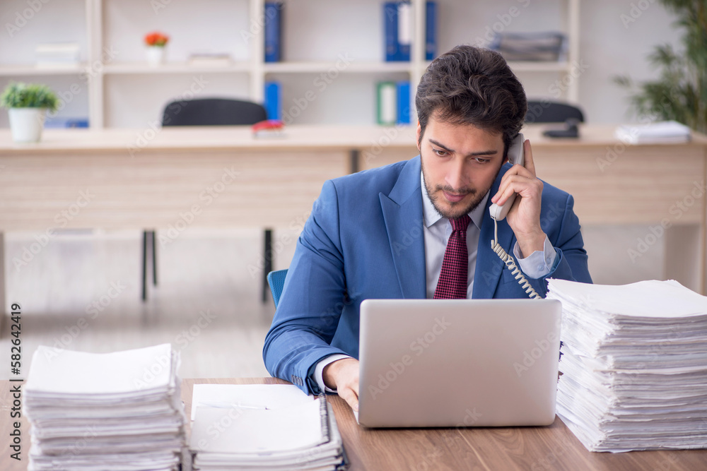 Young male employee and too much work in the office Young male employee and too much work in the office
